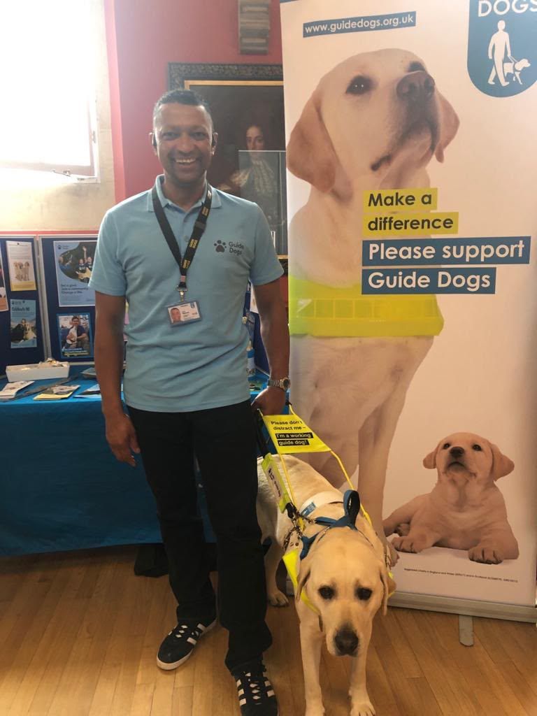 Hugo in his working guide dog harness with his former owner at a Guide Dogs event